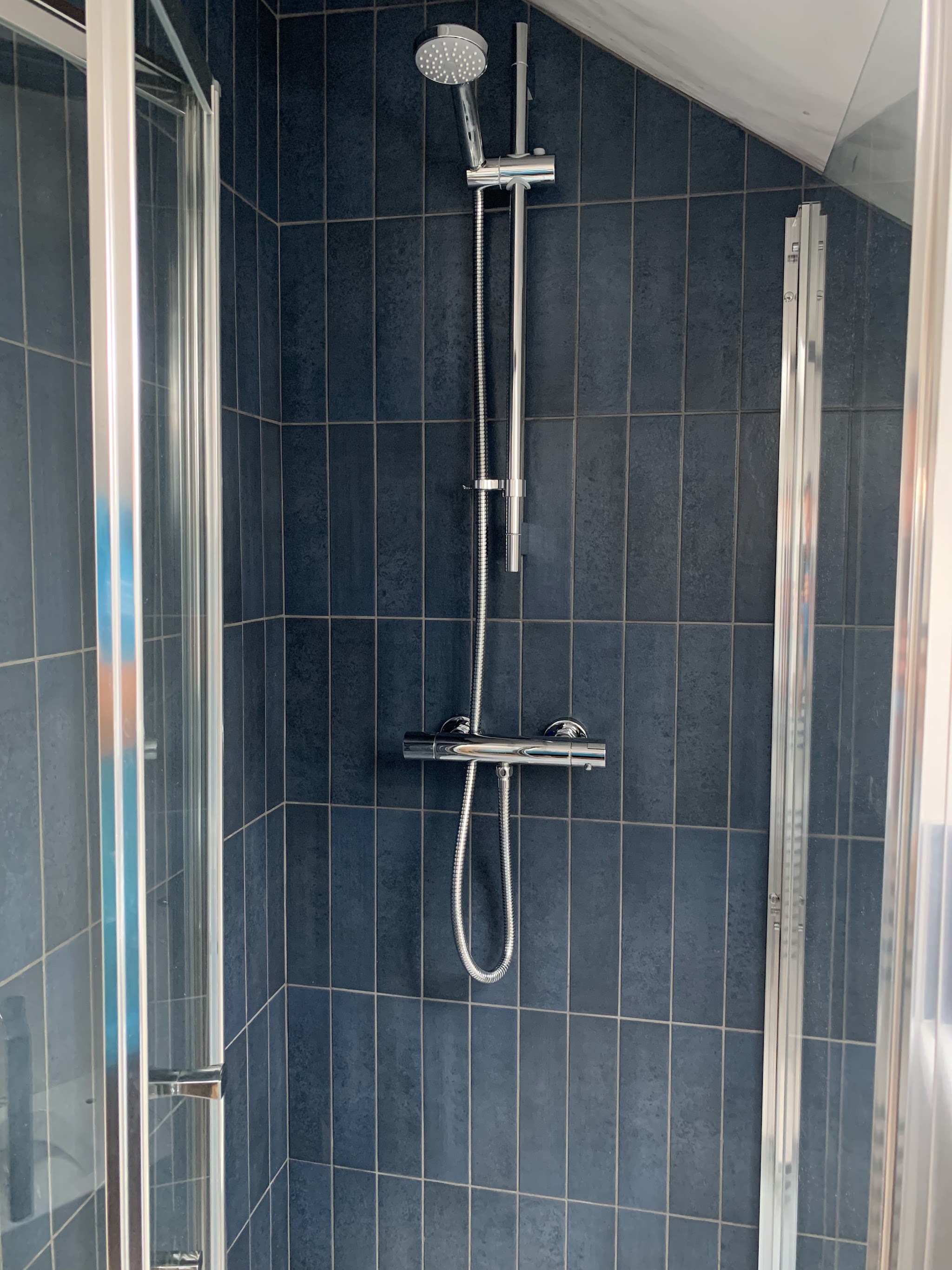Shower with navy vertical tiles and a thermostatic shower