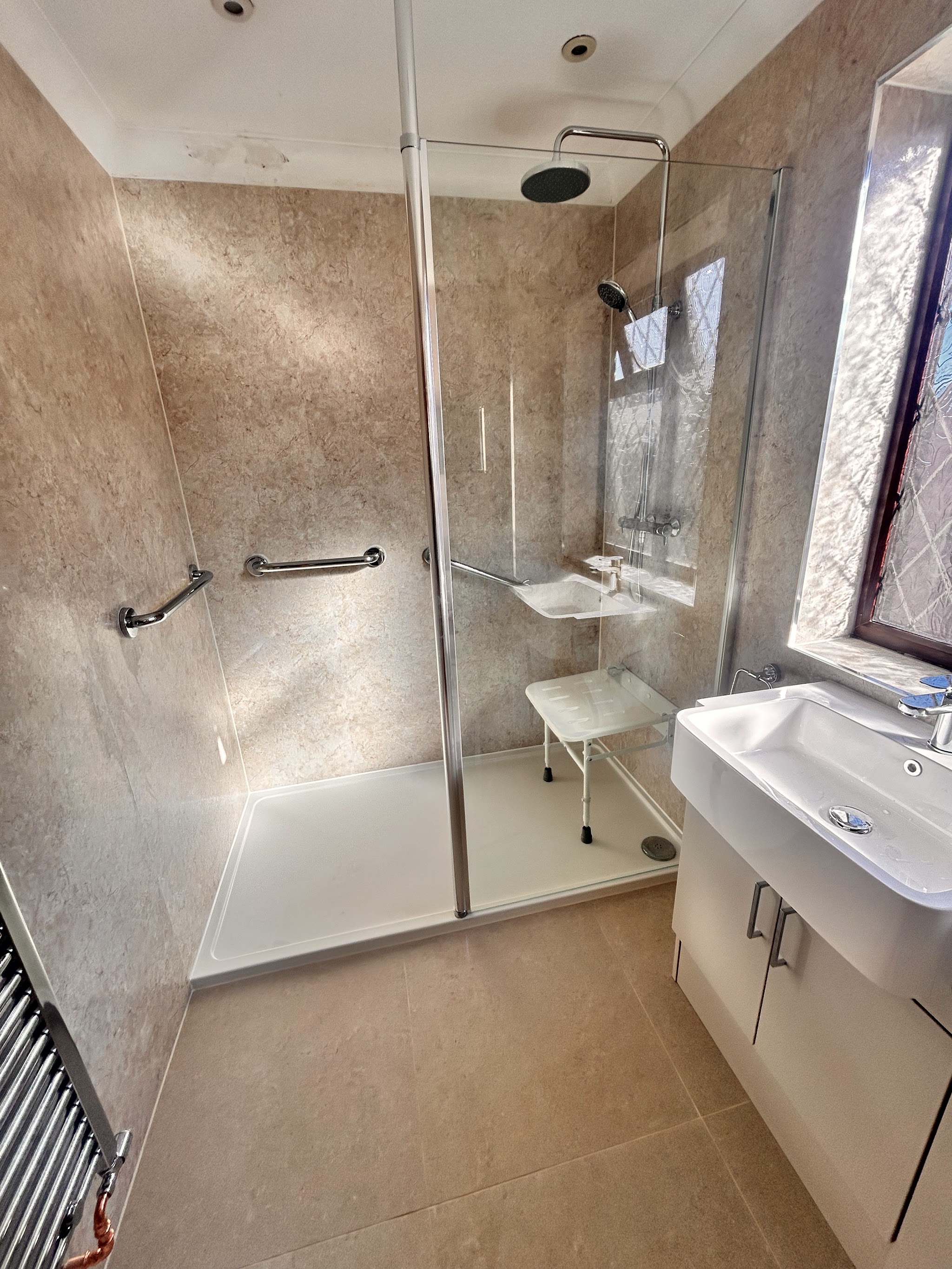 Walk-in shower with grab rails, wall panels and a vanity basin