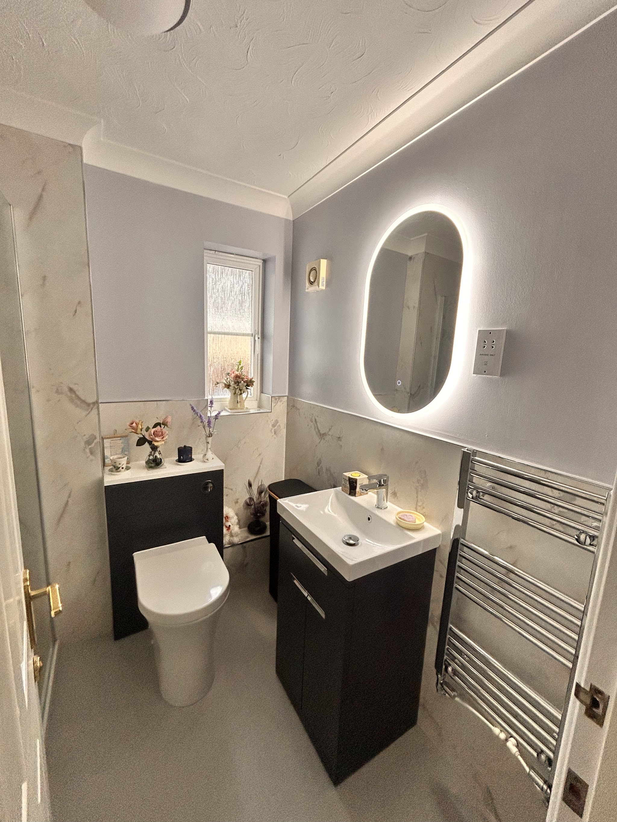 Cloakroom with a navy vanity unit, oval LED mirror and chrome towel rail