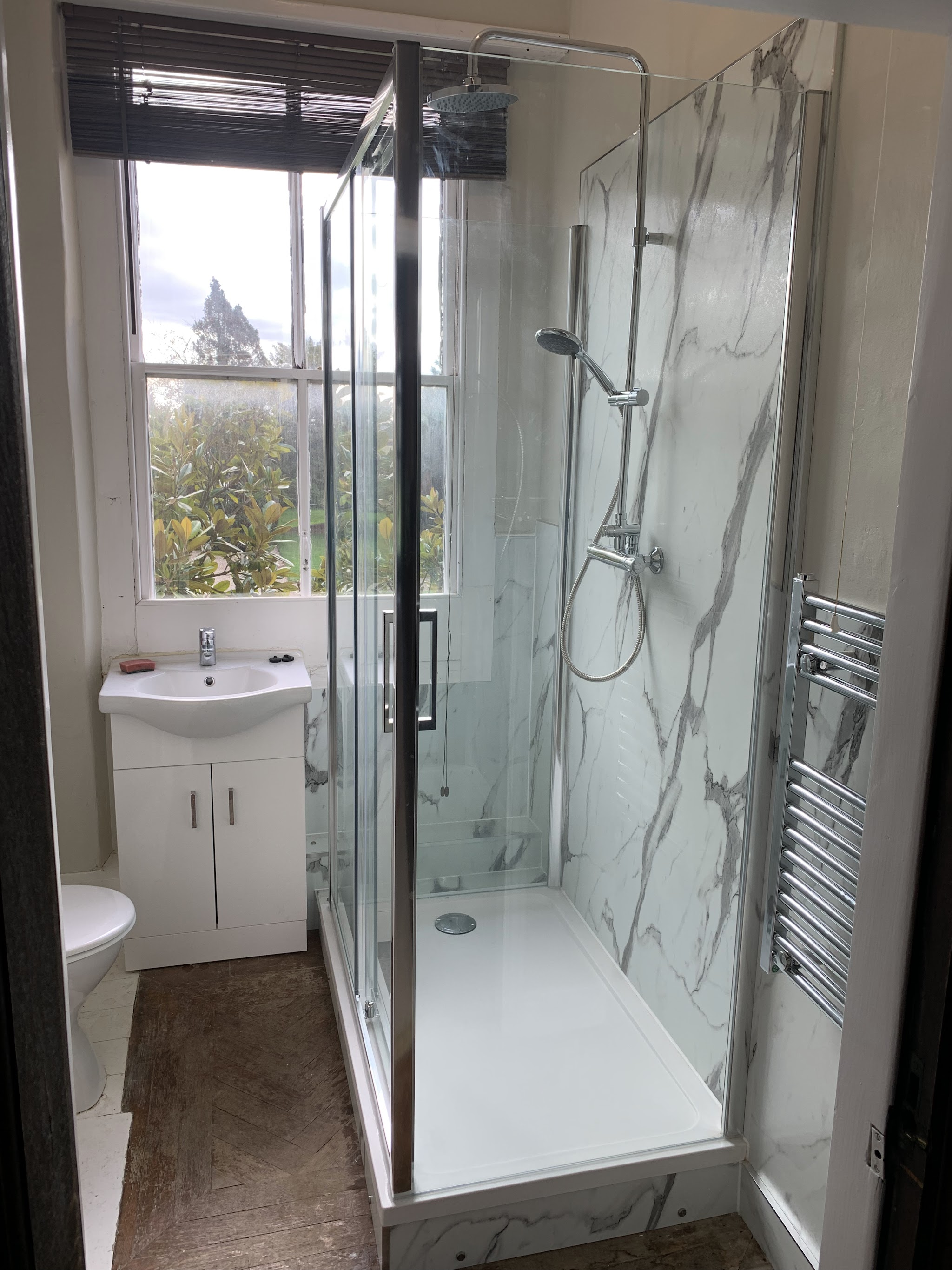 Shower enclosure finished in marble-effect wall panels